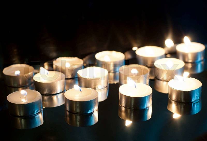 Many burning candles on a black background, stock photo