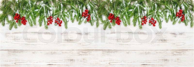 Christmas decoration. Holidays banner. Evergreen tree branches with red berries on wooden background, stock photo