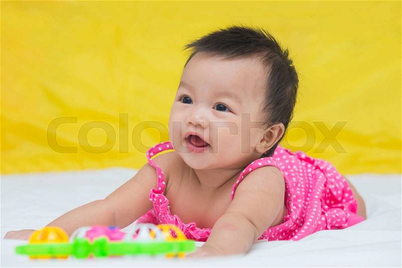 Portrait of cute baby smiling girl on the bed with toy, stock photo