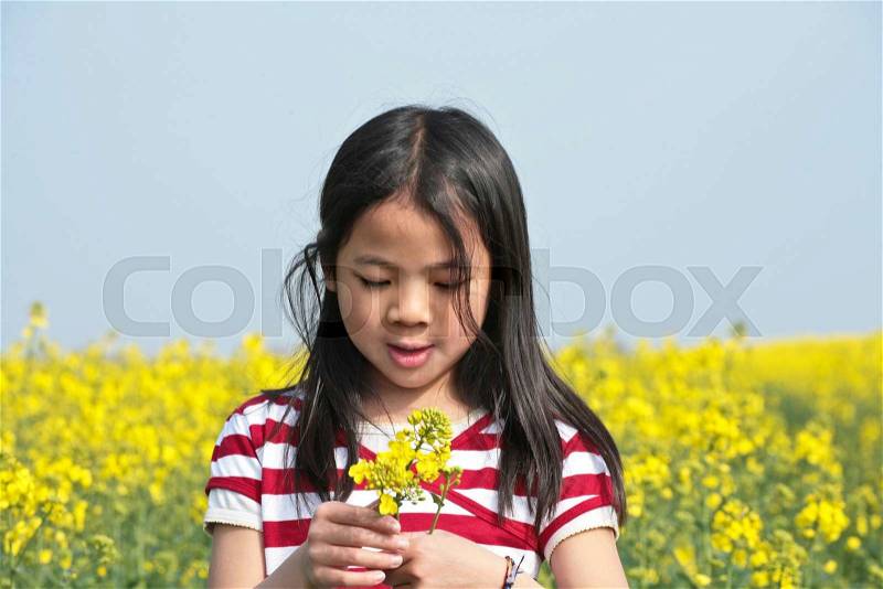 Young girl in a rapse field in the summer in the countryside in denmark, stock photo