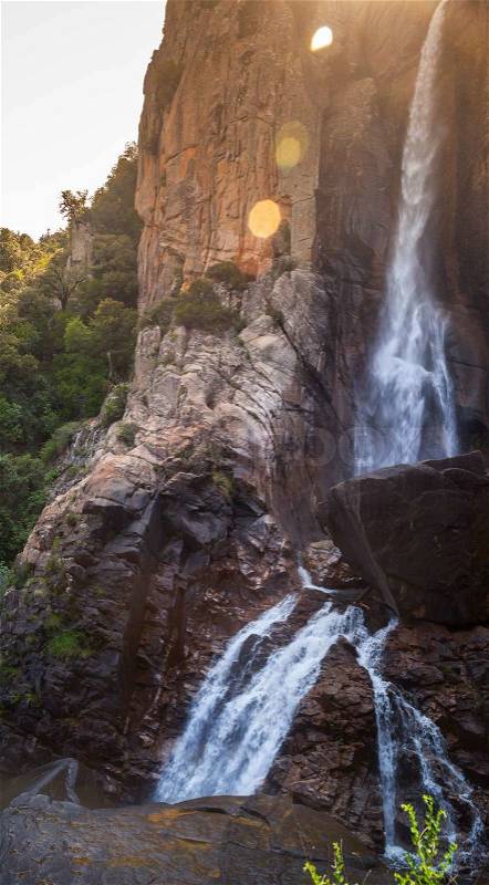 Natural vertical landscape, waterfall in South part of Corsica island, France. Lens flare photo effect, stock photo
