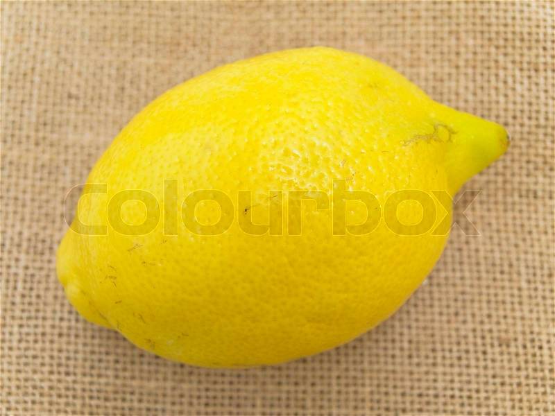 Single lemon at the brown linen, stock photo