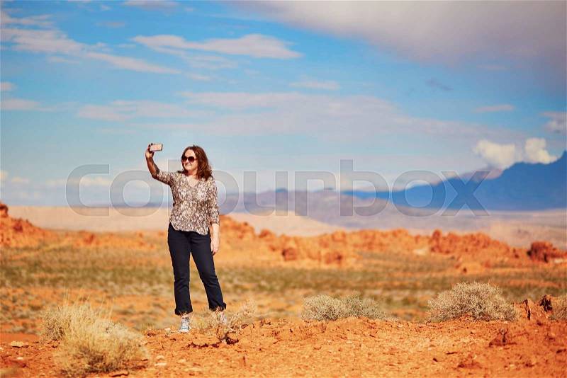Tourist taking photo with her mobile phone in Valley of the Fire national park, Nevada, USA, stock photo