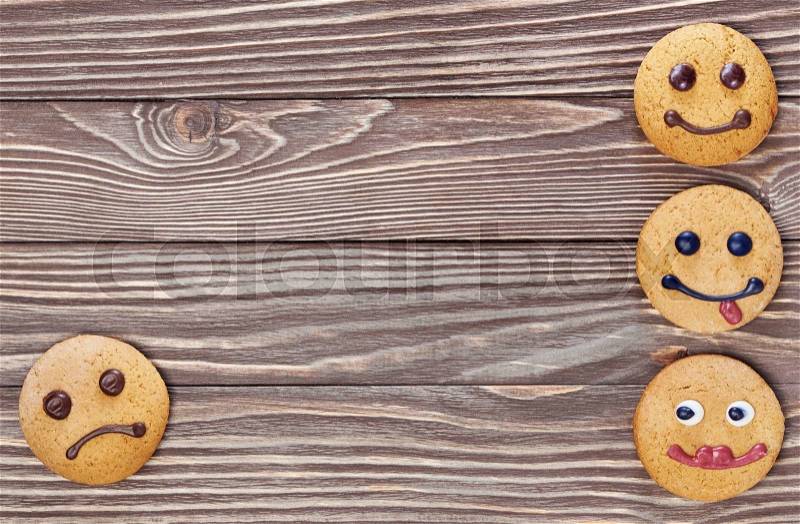 Smiling and sad cookies on wooden background, stock photo