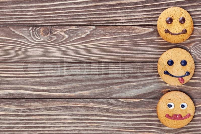 Smiling and sad cookies on wooden background, stock photo