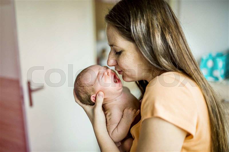 Newborn baby crying in mother hands indoor, stock photo