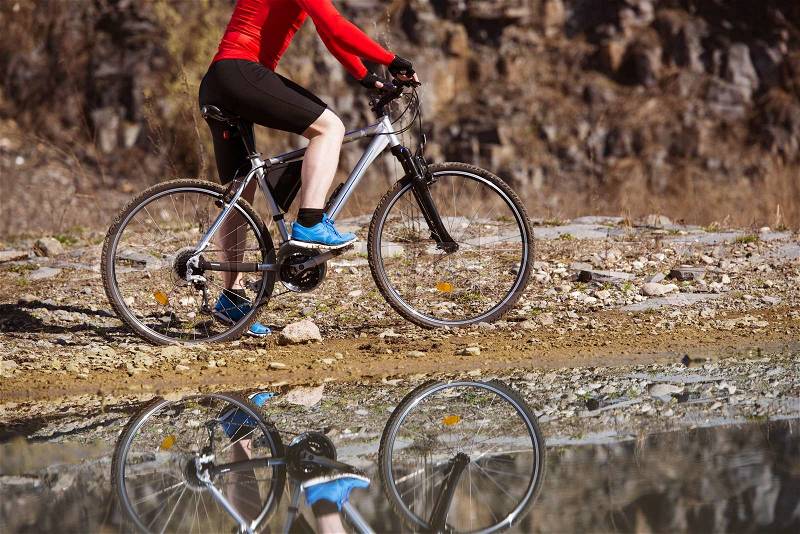 Detail of cyclist man reflecting in water puddle, stock photo
