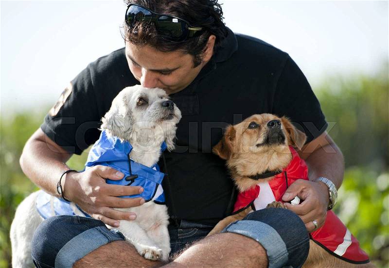 Happy young man is sitting on the grass with his two dogs, stock photo