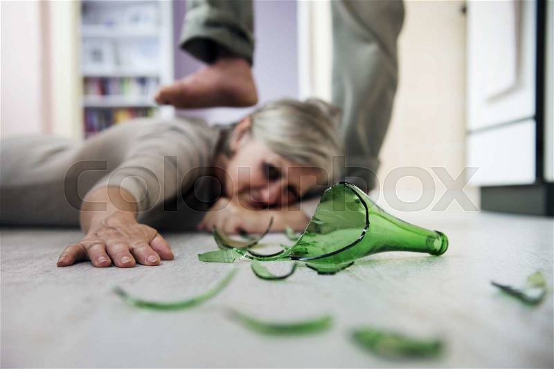 Woman victim of domestic violence and abuse. Mature woman scared of a man with broken bottle, stock photo