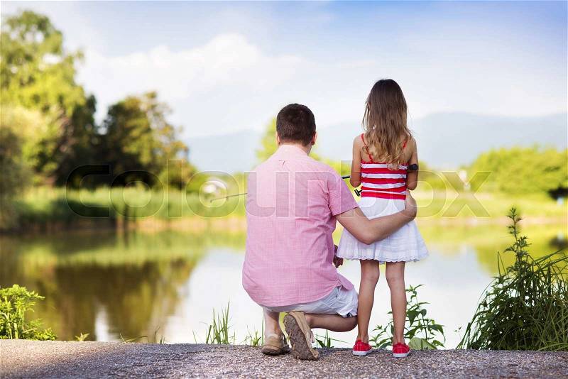 Happy young father fishing on the lake with his little daughter, stock photo