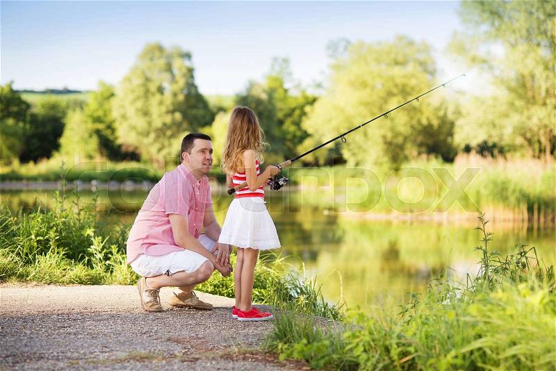 Happy young father fishing on the lake with his little daughter, stock photo