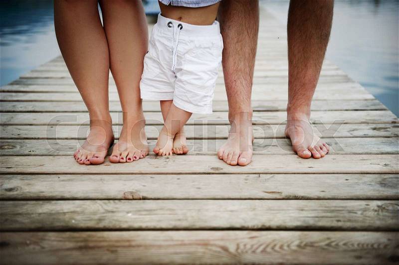 Closeup of feet of family with little baby boy walking on pier, stock photo