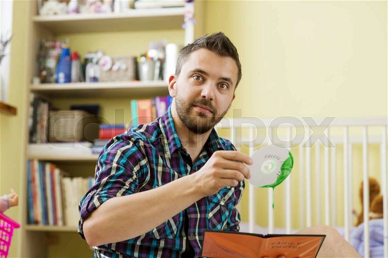 Man holding damaged CD sitting on florr in bedroom, stock photo