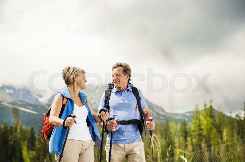 Senior tourist couple hiking at the beautiful mountains, stock photo
