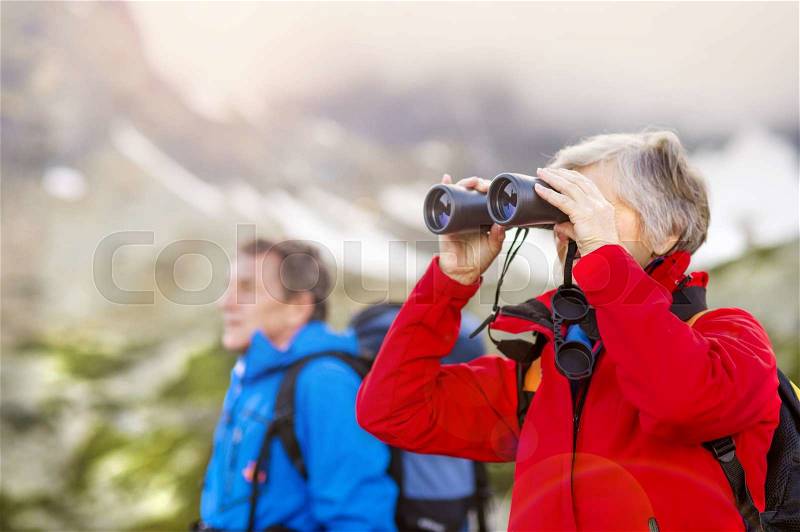 Senior hikers couple enjoying the landscape view with binoculars, stock photo