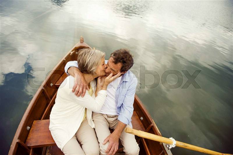 Senior couple kissing on boat on mountain tarn, stock photo