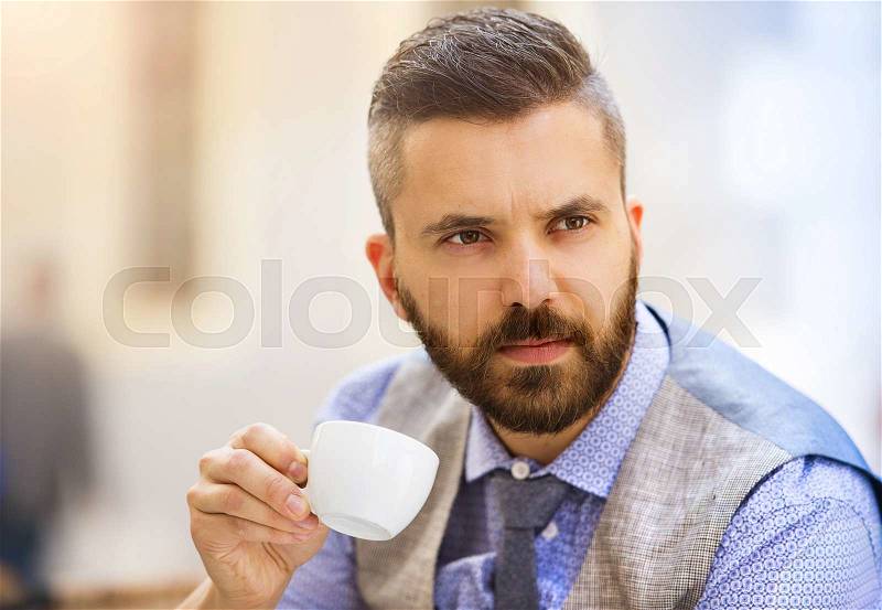 Modern hipster businessman drinking espresso coffee in the city cafe during lunch time, stock photo