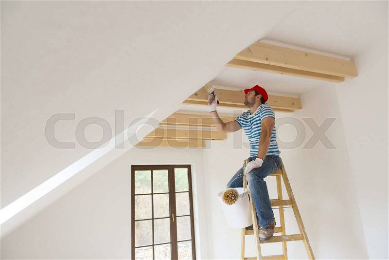 Happy smiling man painting the walls of new home with paintbrush, stock photo