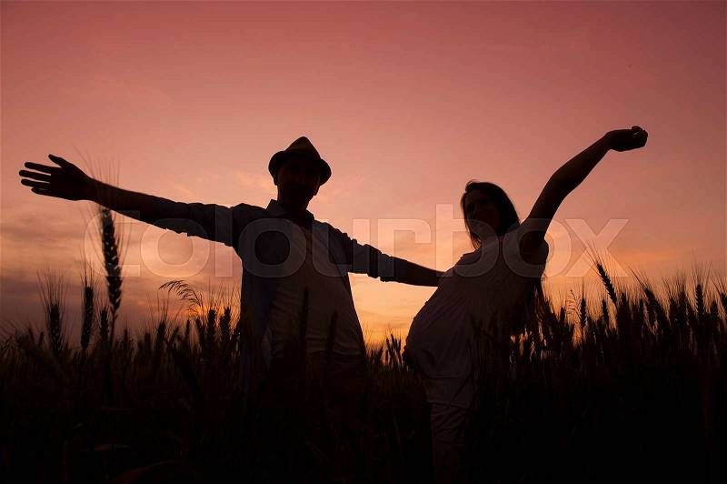 Silhouette of pregnant couple in the sunset, stock photo