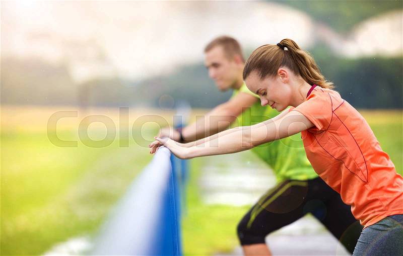 Young couple stretching after the run on asphalt in rainy weather, stock photo