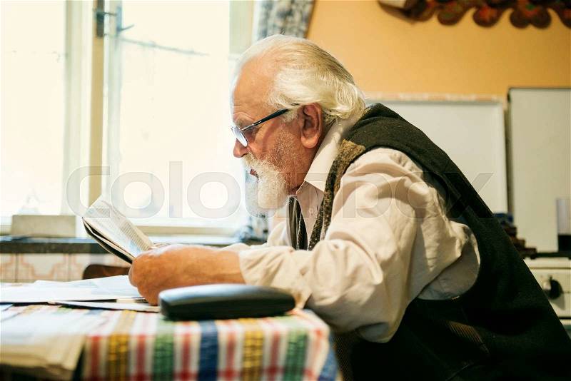 Old man reading the newspaper at home, stock photo