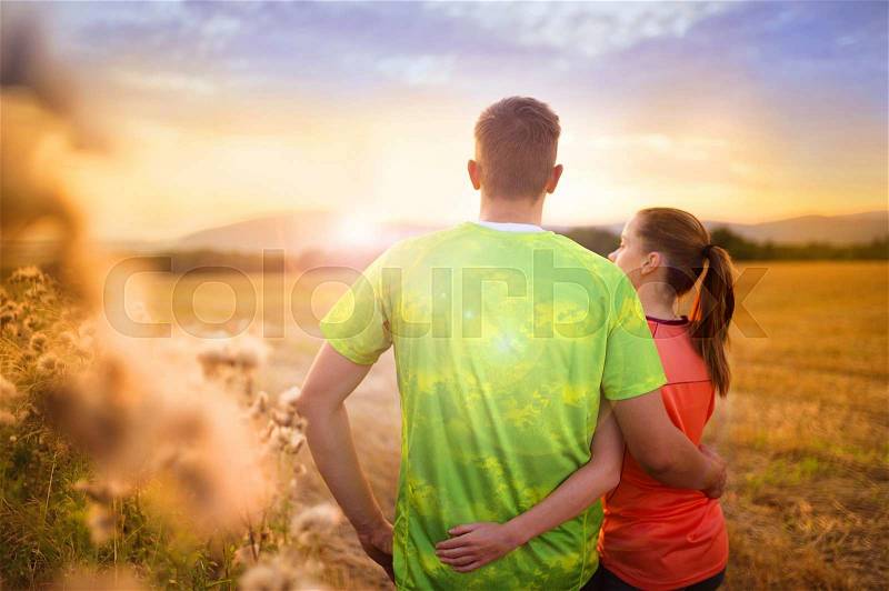 Cross-country trail running couple relaxing and watching the sunset, stock photo