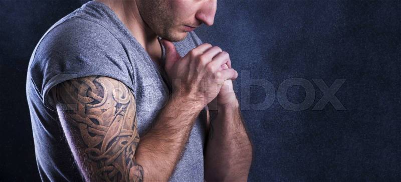 Handsome young man with tattoo, isolated on black, stock photo
