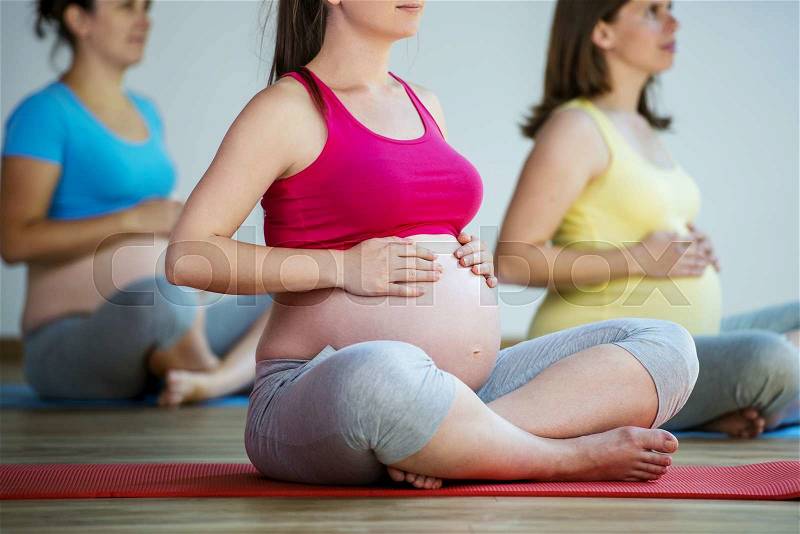 Group of young pregnant women doing relaxation exercise on exercising mat, stock photo