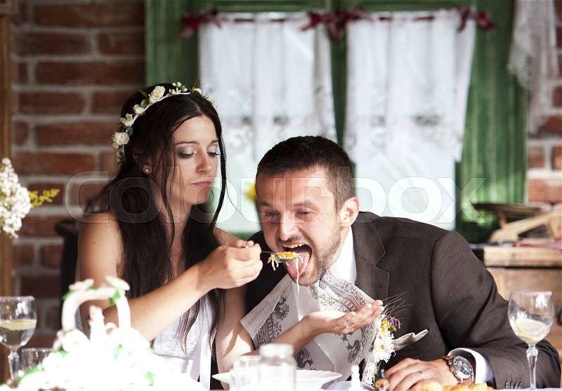 Bride and groom are eating at the wedding reception, stock photo