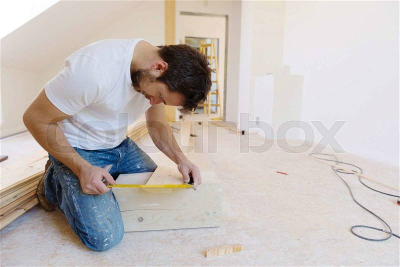 Handyman installing wooden floor in new house, stock photo