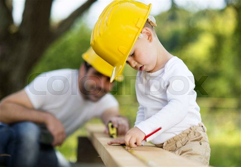 Little son helping his father with building work, stock photo