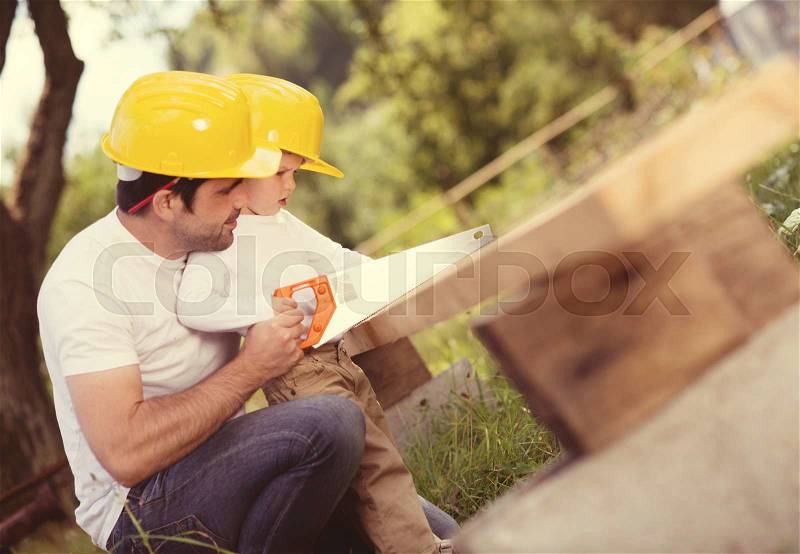 Little son helping his father with building work, stock photo
