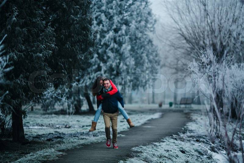 Man carries his girlfriend on his back in the park, stock photo