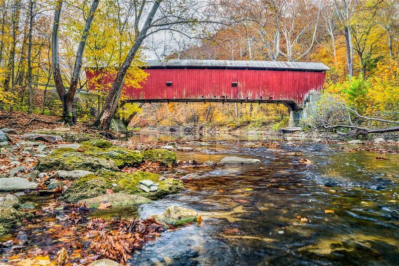 Built in 1915, the Rolling Stone Covered Bridge crosses a Putnam County Indiana stream in autumn, stock photo