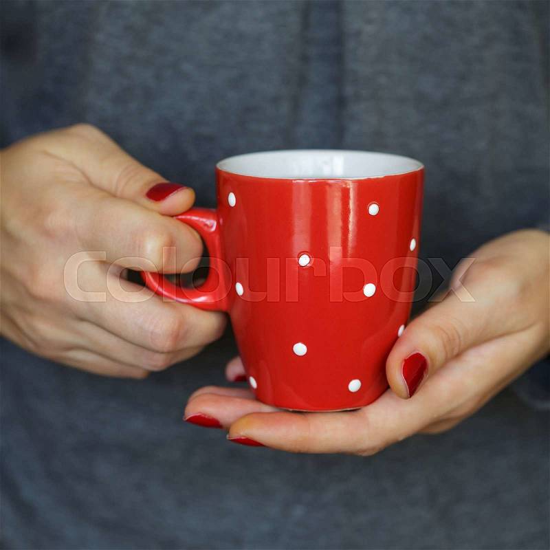 Woman hands holding a cozy red mug. Winter and Christmas time concept, stock photo