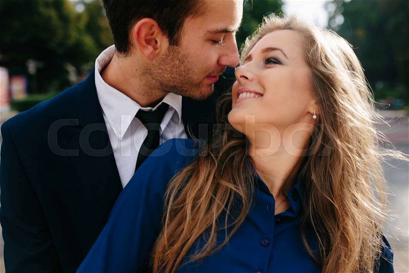 Guy hugging his girlfriend from behind in the city, stock photo