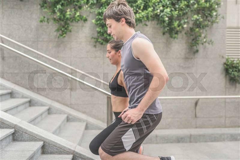 Couple of young handsome caucasian sportive man and woman running upstairs, looking downward - sportive, healthy, fitness concept, stock photo