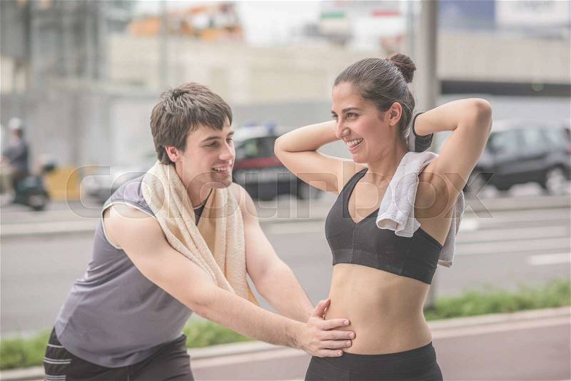 Half length of a couple of young handsome caucasian sportive man and woman stretching.She has arms behind her head and he is doing lunges lying on his friend belly - sportive, fitness ,healthy concept, stock photo