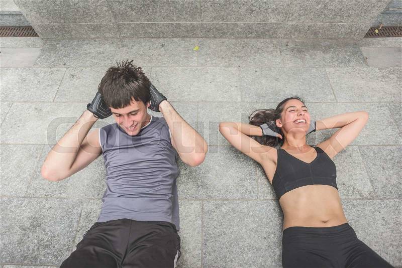 Couple of handsome caucasian sportive man and woman laughing while doing abdominals lying on the floor - sportive, healthy, training, practice, fitness concept, stock photo
