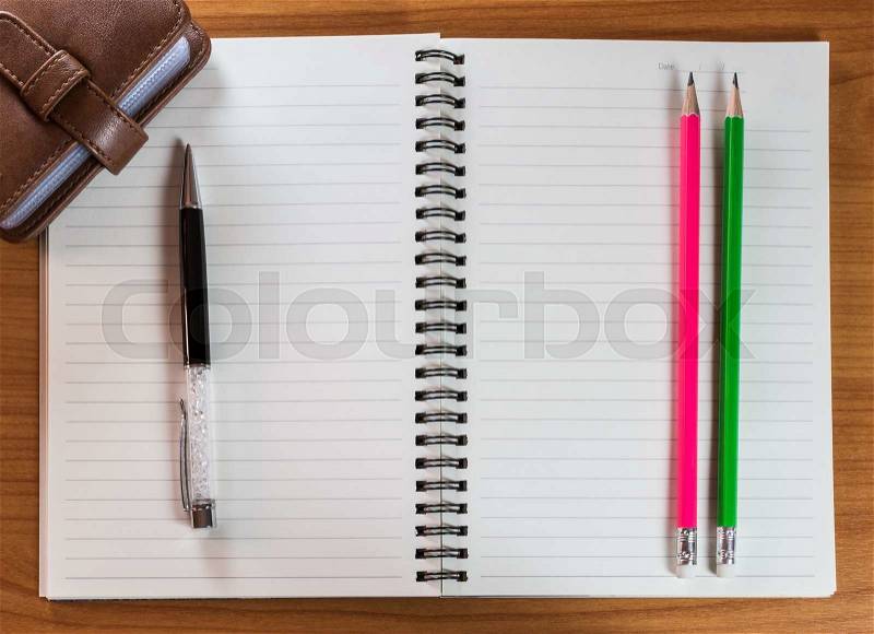 Pen and pencils on notebook with leather bag on wooden table, stock photo