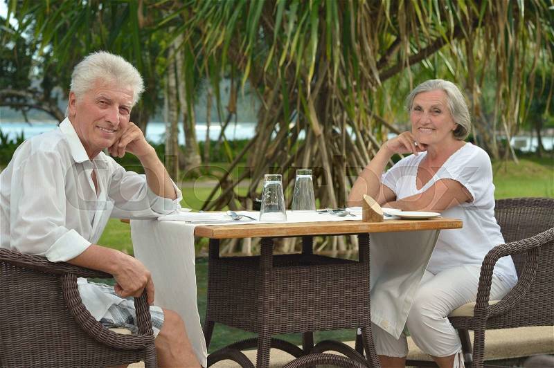 Amusing happy smiling old couple at cafe table, stock photo