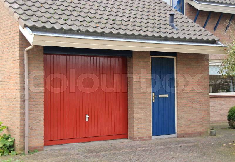 Striking red garage door and the blue back door with a mailbox in the residential area in the village in fall, stock photo