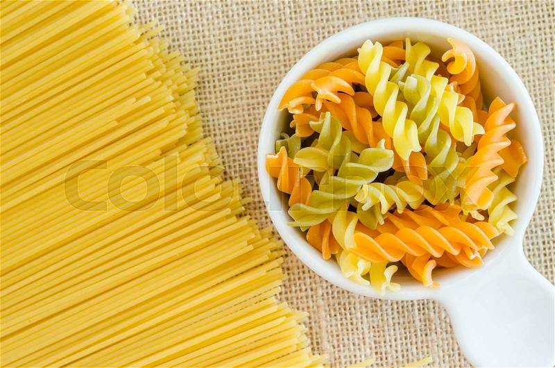 Italian raw pasta with uncooked pasta spaghetti macaroni on sack background, stock photo