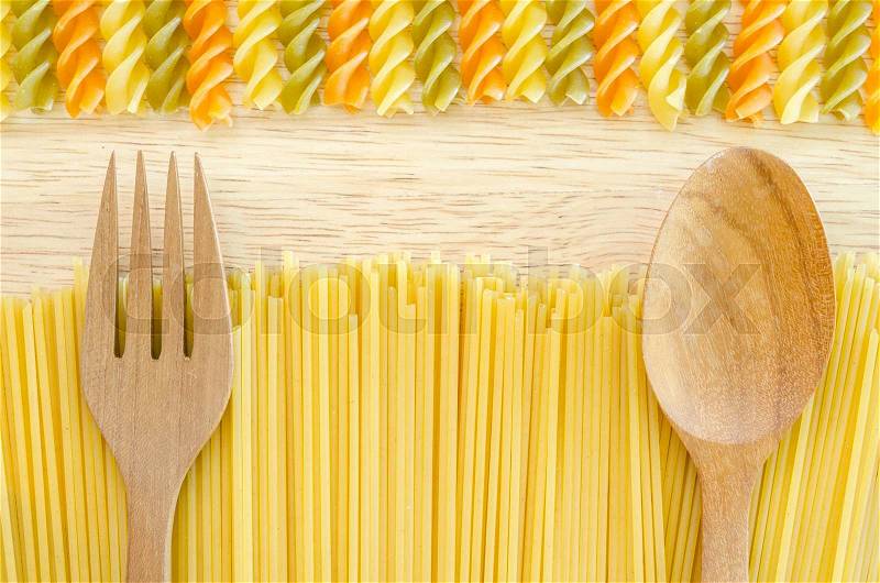 Italian raw pasta with uncooked pasta spaghetti macaroni on wooden background, stock photo