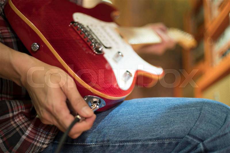 Closed up hand holding jack plug-in to the electric guitar, shallow DOF, selected focus, stock photo