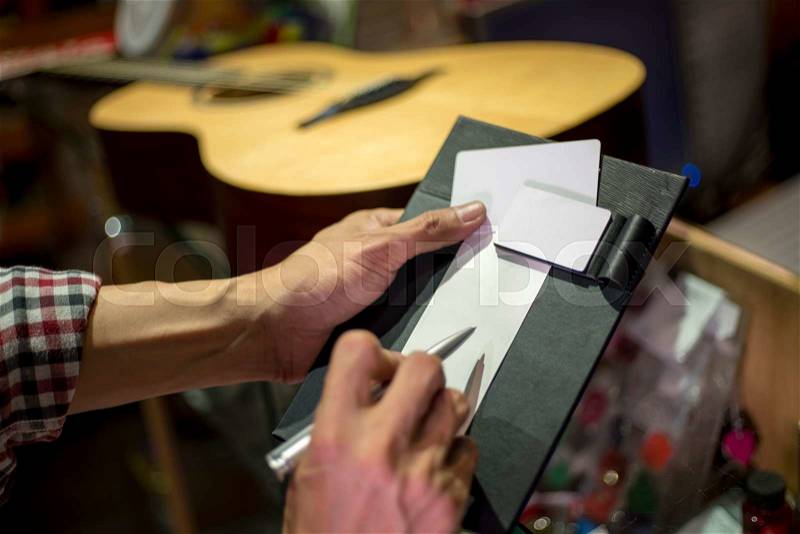 Customer signing on sale slip accept to buy guitar, shallow DOF, selected focus, stock photo