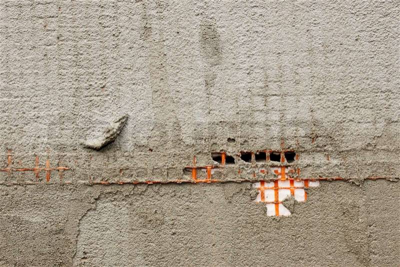 Detail of a wall covered with orange plastic mesh and construction glue, stock photo