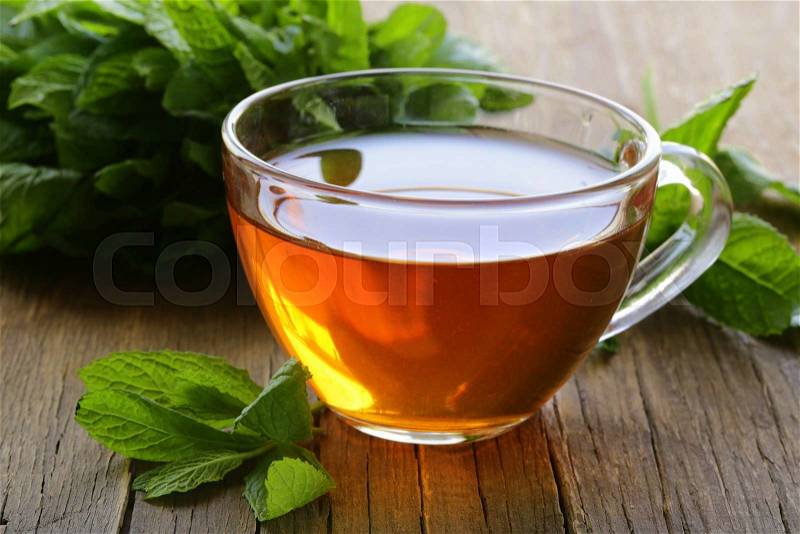 Cup of tea with mint and honey on a wooden table, stock photo