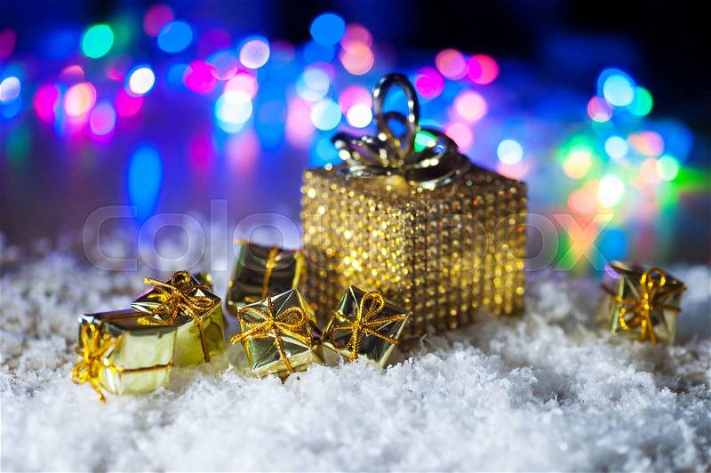 Christmas present in gold wrapping with ribbon on winter background, stock photo
