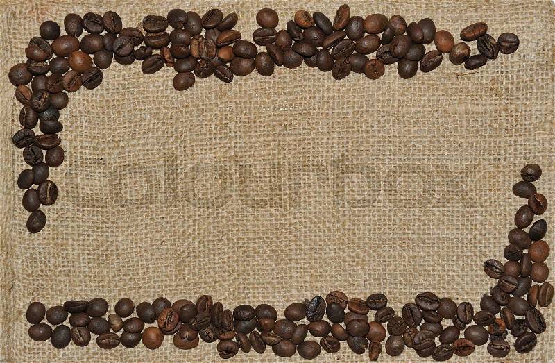 Spilled coffee beans frame over burlap textile, stock photo